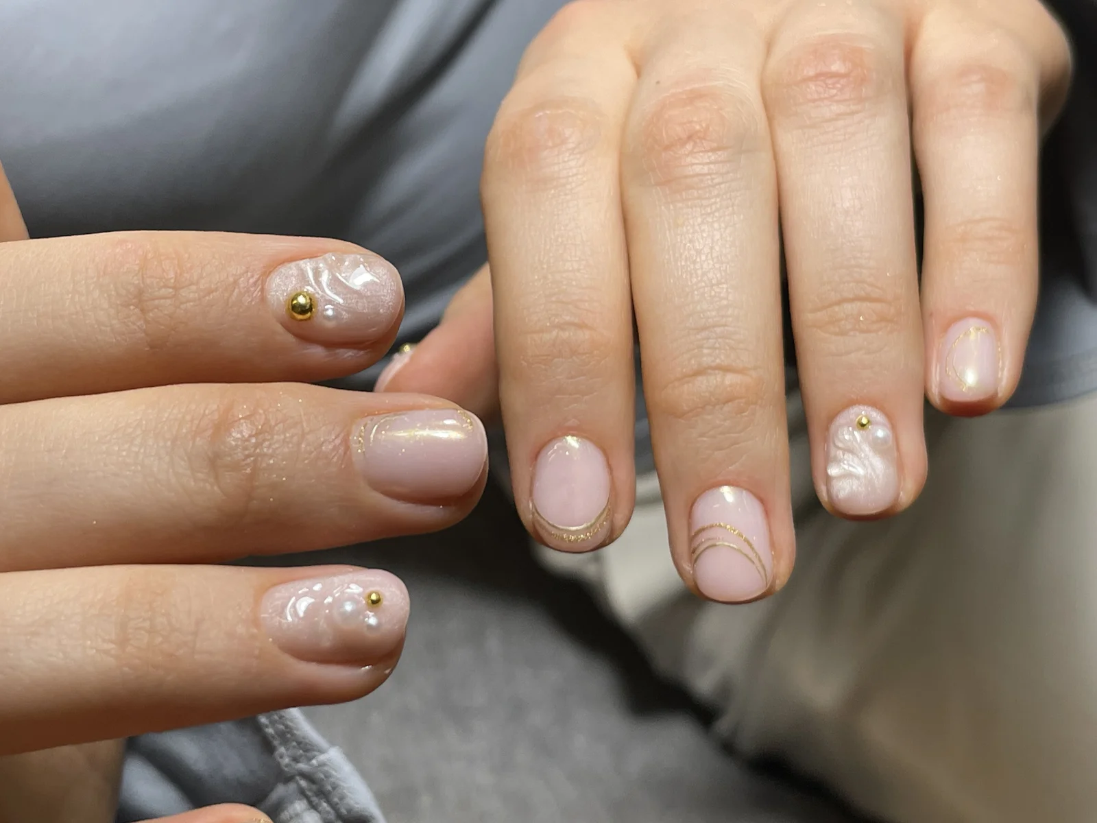 Manicure hybrydowy nude ze złotymi liniami i perłami, wykonany w Norm